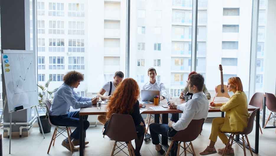 Happy business people gathered around table in office