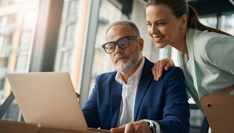 Male and female collegues working with laptop in office